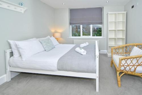 a white bedroom with a bed and a chair at Hale View by YourStays in Altrincham