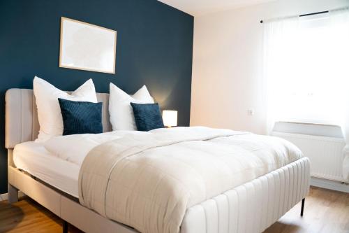 um quarto com uma grande cama branca com paredes azuis em Gemütliches Design Appartment in Wolfsburg em Wolfsburg