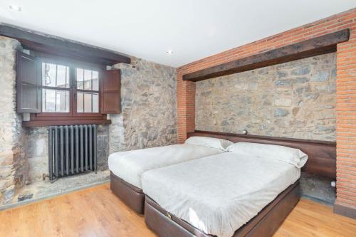 two beds in a room with a stone wall at LA CASA DE LA RIBA in Luanco