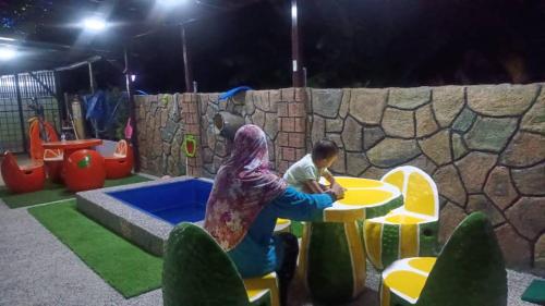 une femme et un enfant jouant dans une aire de jeux dans l'établissement Airport Kota Bharu Homestay & Riverview Inn, à Kota Bharu