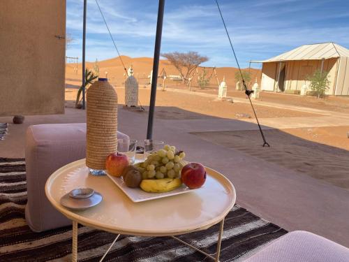 a tray of fruit on a table with a drink at Merzouga Heart Luxury Camp in Merzouga