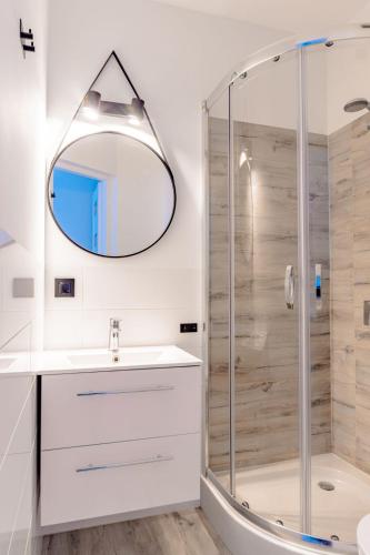 a bathroom with a shower and a sink and a mirror at Willa Bliźniak - Pokoje i Apartamenty Bardzo Blisko Plaży in Karwia