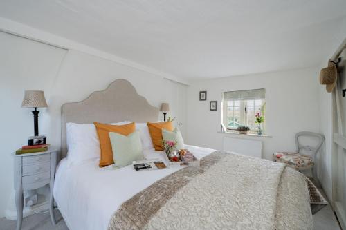 a bedroom with a large white bed with orange pillows at Tudor Rose Cottage in Stourpaine