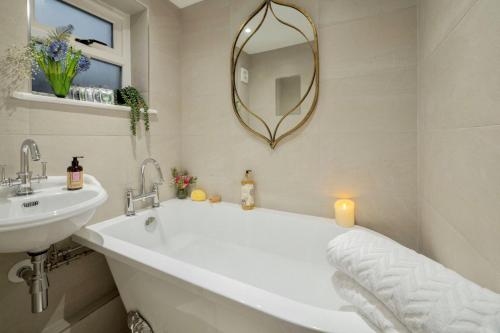 a bathroom with a tub and a sink and a mirror at Tudor Rose Cottage in Stourpaine