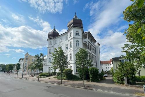 ein weißes Gebäude mit einem Turm auf einer Straße in der Unterkunft Ferienwohnung 10 Haus Metropol in Binz