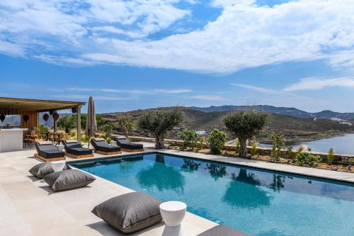 basen z krzesłami i widokiem na wodę w obiekcie Panormos Bay Suites Luxury Resort w mieście Panormos Mykonos