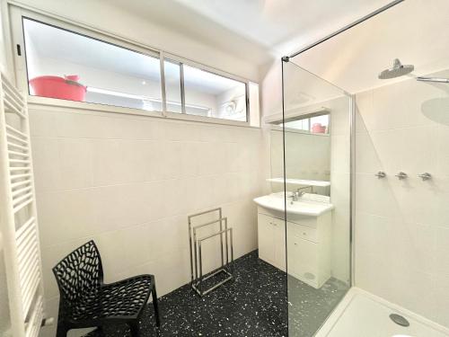 La salle de bains est pourvue d'une douche en verre et d'une chaise. dans l'établissement Appartement le Sicile sanguinaires Ajaccio, à Ajaccio