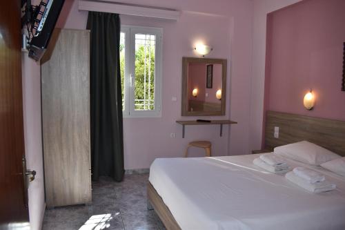 a bedroom with a white bed and a window at Eden Beach Hotel in Agia Marina Nea Kydonias