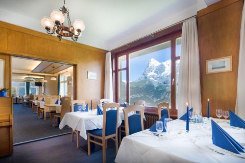 a restaurant with tables and chairs with a mountain view at Hotel Alpina in Mürren