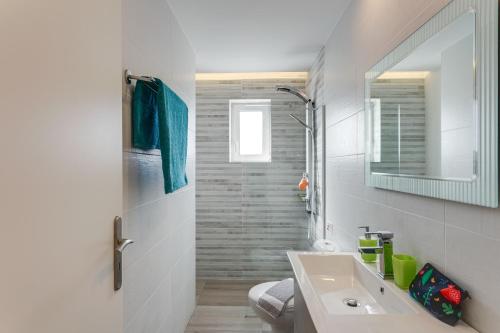 a white bathroom with a sink and a mirror at Eden Beach Hotel in Agia Marina Nea Kydonias