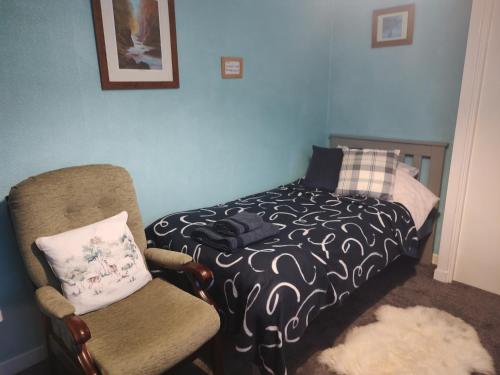 a small bedroom with a bed and a chair at Cartmel in Aultbea
