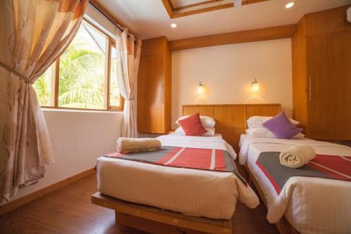 two beds in a room with a window at Island Pavilion in Hangnaameedhoo