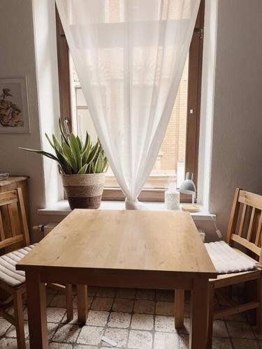 a wooden table in front of a window with a potted plant at Pretty Home City Lounge in Zwickau