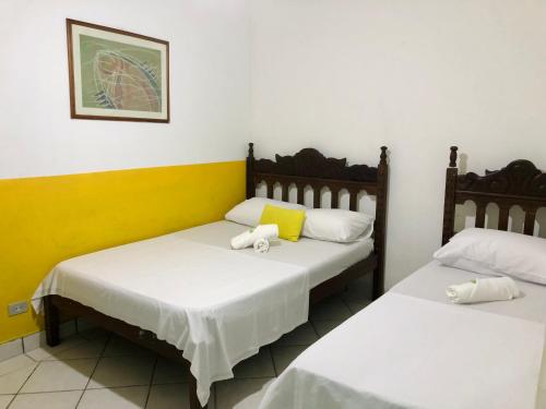 Duas camas num quarto com paredes amarelas e brancas em Pousada Coco Verde em Paraty