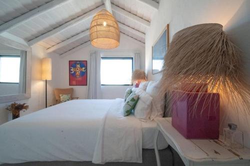 Casa Mimosa, Comporta في كومبورتا: امرأة تجلس على سرير في غرفة النوم