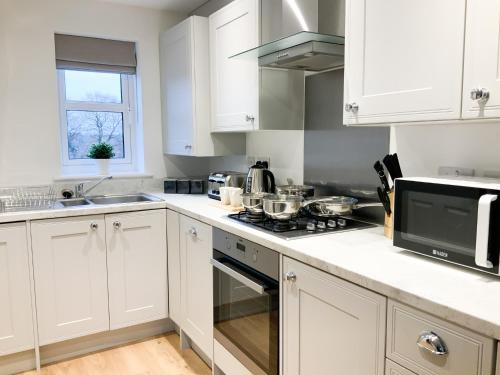 a kitchen with white cabinets and a stove top oven at Jockey house in Andover