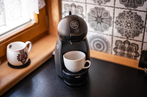a coffee maker sitting on a counter next to two cups at HRYCÓWKA Domki z Widokiem in Grywałd