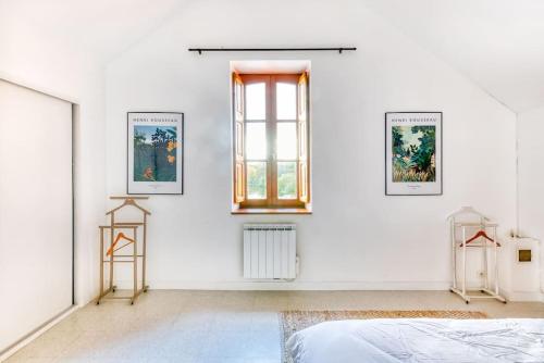 Cette chambre blanche dispose d'un lit et de 2 photos encadrées sur le mur. dans l'établissement Moulin de charme - 5 personnes, à Saint-Sulpice