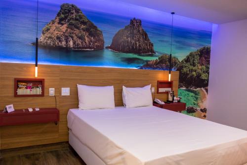 ein Schlafzimmer mit einem großen Bett und einem Gemälde an der Wand in der Unterkunft Suítes Alvorada in Rio Verde