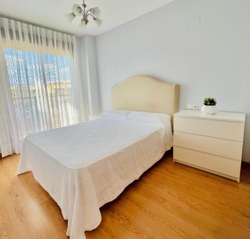 a bedroom with a white bed and a dresser and window at Apartamento apto para bebés con parking privado in Almazora