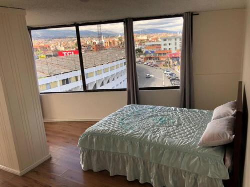 a bedroom with a bed and a large window at Mirador del Estadio in Cuenca