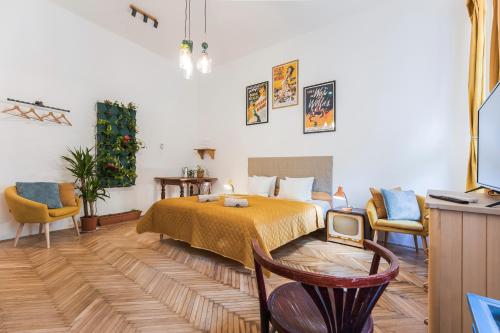 um quarto com uma cama e duas cadeiras e uma televisão em BudapeStayz - Lónyay Studios em Budapeste