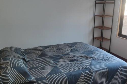 a bed with a blue comforter in a room at Cabañas en la naturaleza in Villarrica