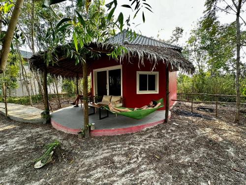 een klein huis met een hangmat ervoor bij A Maze Inn Cottage in Phumĭ Chroŭy Svay