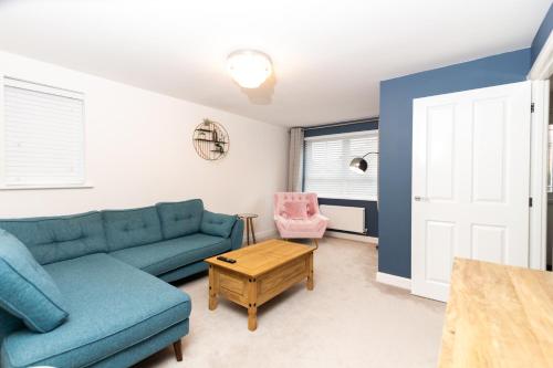 ein Wohnzimmer mit einem blauen Sofa und einem Tisch in der Unterkunft Cosy Home with Garden in a Picturesque Village in Hull