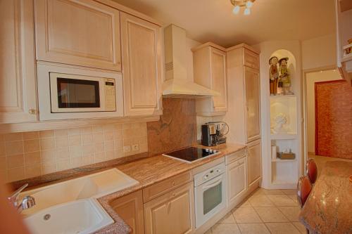 une cuisine avec des armoires blanches, un évier et un micro-ondes dans l'établissement Appartement les Horizons sanguinaires Ajaccio, à Ajaccio