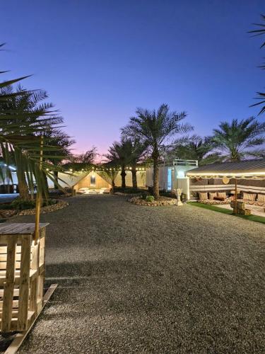 a driveway with palm trees and a house at Hatta Farm caravan in Hatta