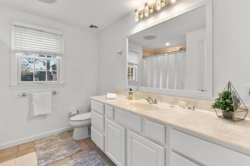 a white bathroom with a sink and a toilet at Colonial Vacation Home w Private Pool fire pit and spacious backyard in Falmouth