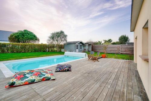 une cour arrière avec une piscine et une terrasse en bois dans l'établissement Maison avec piscine pour 8 - 500m de la plage, à Plobannalec-Lesconil