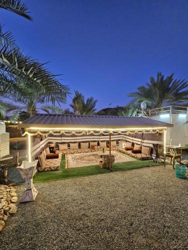 a house with a pavilion with furniture and palm trees at Hatta Farm caravan in Hatta