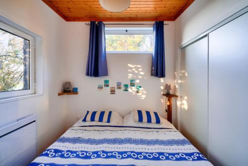 - une chambre avec un lit doté de rideaux bleus et d'une fenêtre dans l'établissement 500m de la plage - Séjour à 4 avec Hoomy, à Loctudy