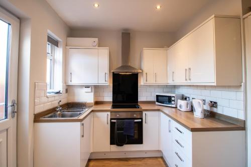 a kitchen with white cabinets and a sink at Charming Middlesbrough Home in Middlesbrough