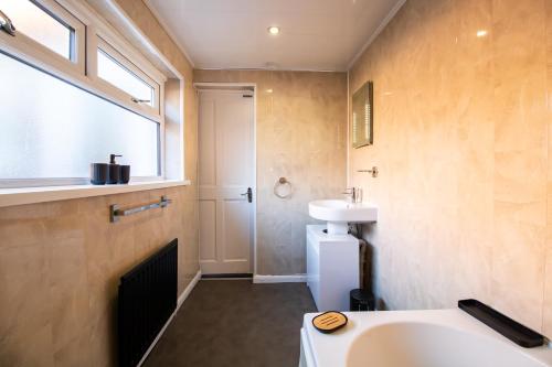 a bathroom with a sink and a toilet and a window at Charming Middlesbrough Home in Middlesbrough