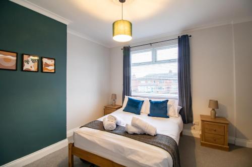 een slaapkamer met een bed met blauwe kussens en een raam bij Charming Middlesbrough Home in Middlesbrough