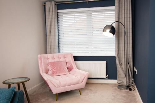 una sedia rosa seduta in una stanza con finestra di Cosy Home with Garden in a Picturesque Village a Hull