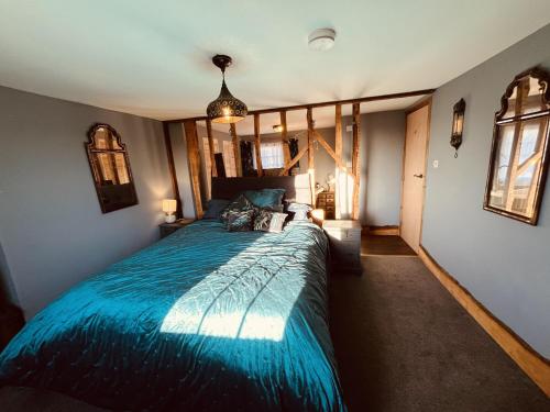 a bedroom with a large bed with a blue comforter at 3 bedroom Quirky Luxurious Cottage With Hot Tub in Heathfield
