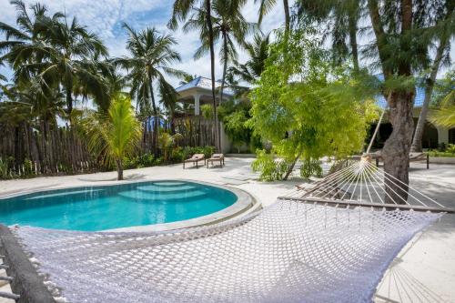 a hammock in a yard with a pool and palm trees at RoRi Private Luxury Villas in Bwejuu