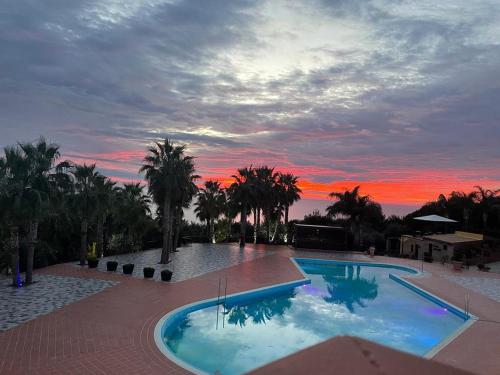 a large swimming pool with a sunset in the background at Baia Di Ulisse Wellness & Spa in San Leone