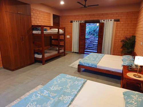 a bedroom with two beds and a bunk bed at Sereno Barn Eco Stay Chikmagalur in Chikmagalūr