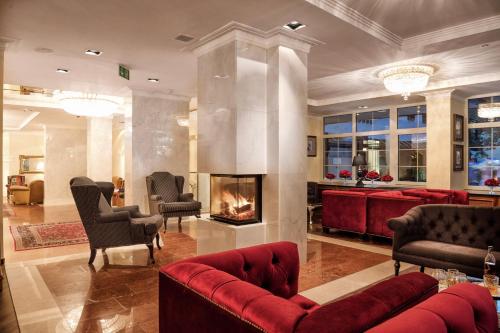 a living room with a red couch and a fireplace at Hotel Norica - Thermenhotels Gastein mit dem Bademantel direkt in die Therme in Bad Hofgastein