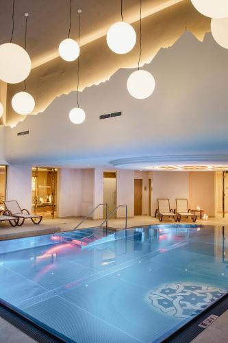 a swimming pool in a large room with lights at Hotel Norica - Thermenhotels Gastein mit dem Bademantel direkt in die Therme in Bad Hofgastein