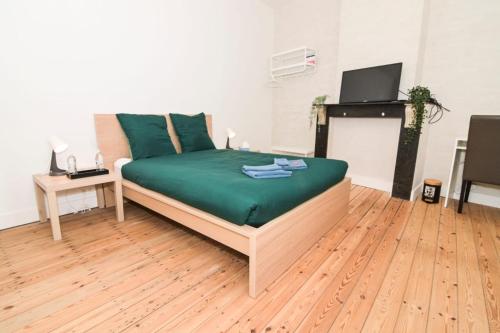a bedroom with a bed with green sheets and a tv at Cozy and confortable room near Brussels Central Station in Brussels
