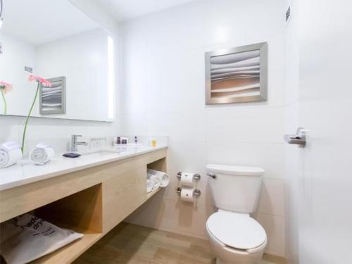 biała łazienka z toaletą i umywalką w obiekcie Gran Hotel de Puebla by HNF w mieście Puebla