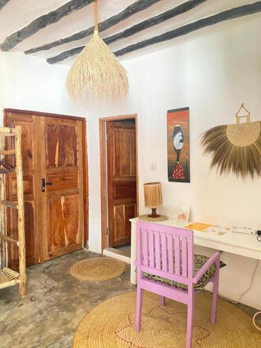 a room with a desk and a pink chair at FURAHA BEACH ROOMS in Kendwa
