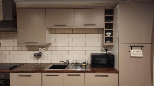uma cozinha com um lavatório e um micro-ondas em Large 2 Bed Holiday Let in Central Ystradgynlais em Ystradgynlais