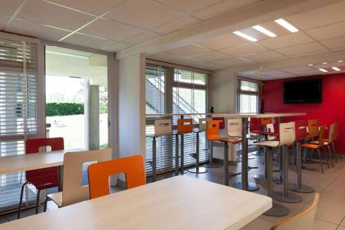 une salle à manger avec des tables, des chaises et des murs rouges dans l'établissement HOTEL PREMIERE CLASSE Rouen Sud Oissel, à Saint-Étienne-du-Rouvray